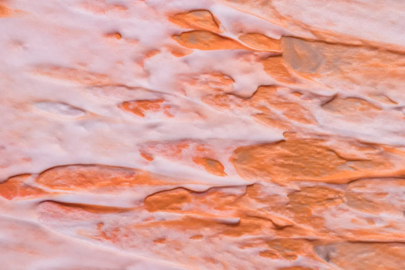 Draufsicht auf ein grob texturiertes orangefarbenes Farbmuster auf Fliesen.